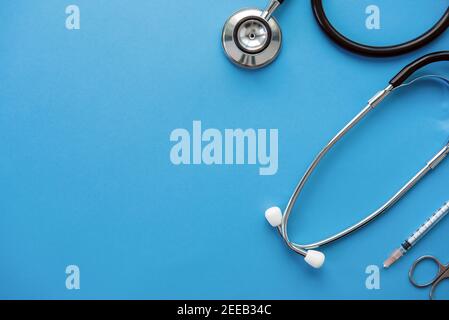 Medical instruments including stethoscope, scissors and syringe on light blue background, top view with copy space Stock Photo