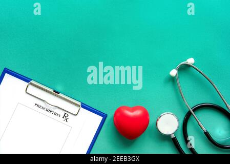 Stethoscope, rx prescription and red heart shape ball on green paper, medical background top view with copy space Stock Photo