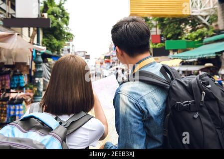 Couple tourist backpackers looking at the map while traveling in Khao San road Thailand on holidays Stock Photo