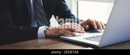 Bussinessman working on laptop computer at the table in the office, parnoramic banner Stock Photo