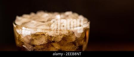 Close up of cold sparking cola sodar soft drink in the glass with foam bubble on top, panoramic banner with copy space Stock Photo