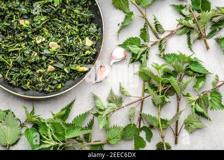 Cooking green vegetables. Healthy food, vegetarian pesto with green nettle and fresh stinging nettles, leaves fried with garlic and spices on frying p Stock Photo