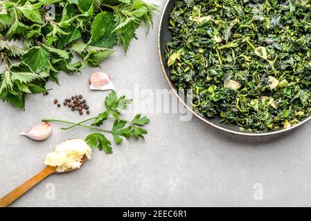 Cooking green vegetables. Healthy food, vegetarian pesto with green nettle and fresh stinging nettles leaves fried with garlic and spices on frying pa Stock Photo