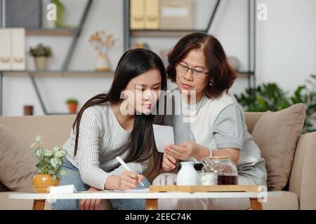 Helping mother with home bookkeeping Stock Photo