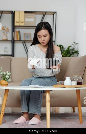 Young woman calculating expenses Stock Photo