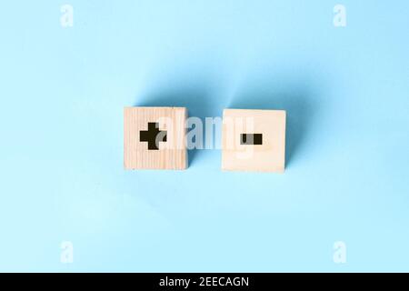 Wooden block in hand on a blue background with plus and minus signs. Decision making business concept Stock Photo