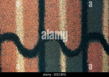 Shingle roof texture background. Roofing material. Dense of rough brown, green, black, yellow granules surface of shingle roof texture background. Stock Photo
