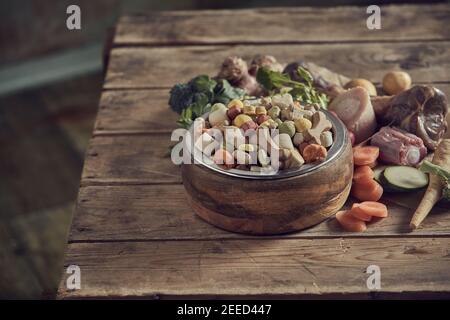 Healthy balanced nutrition for your pet dog with dried pellets or biscuits heaped in a bowl surrounded by assorted fresh vegetable ingredients and mea Stock Photo
