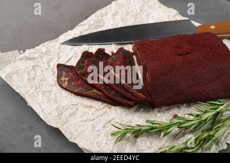 Cut basturma meat product with parsley on parchment Stock Photo