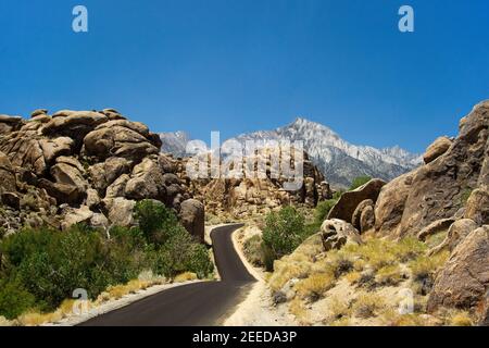 The rocks of 'Alabama Hills' with a winding road and the Sierra Nevada in the background. Stock Photo