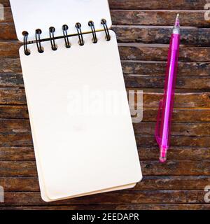 Spiral notepad blank page and pencil on wooden background. Empty sketchbook top view photo. White paper notepad mockup for social media. Summer vacati Stock Photo