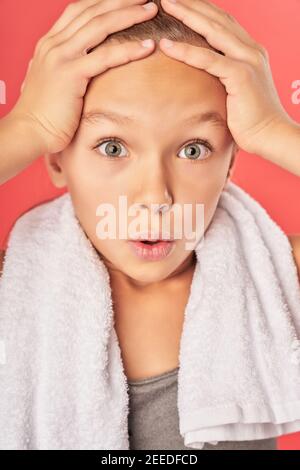 Close up of adorable girl with towel around her neck looking at camera with astonished expression Stock Photo