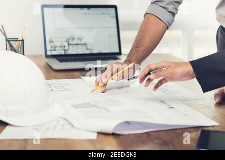 Architect or engineer team discussing a project design using blueprints and a laptop computer at the office before visiting work site. Stock Photo