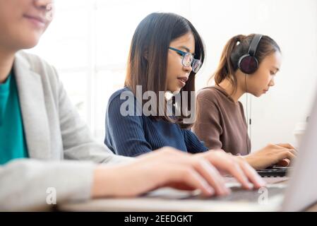 Foreign exchange female asian students doing online work on their laptops in a classroom Stock Photo
