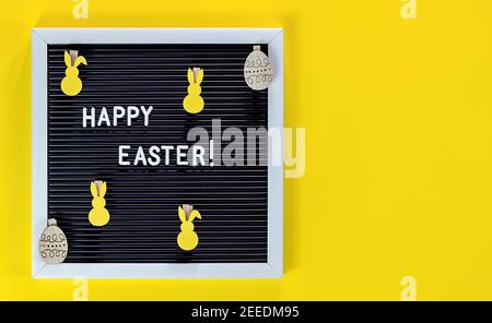 Easter bunny and letter board on yellow background. Flat lay of Easter celebration concept. Stock Photo