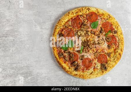 Fresh italian pizza with mushrooms, ham, tomatoes, cheese on on light background.  Stock Photo