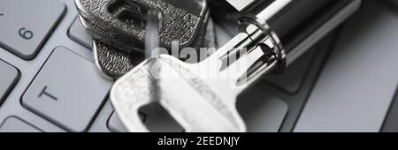 Silver key with lock lie on white keyboard closeup backround. Stock Photo