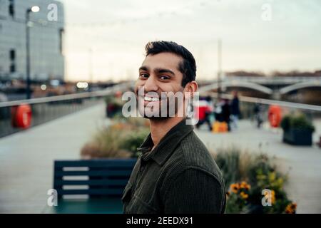 Portrait young mixed race male adult smiling standing on harbour board walk Stock Photo