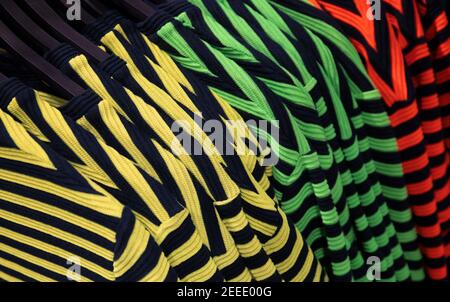 Striped T-shirts on shop's hang. Bright streetwear clothes photo. Stylish striped print on top garment. Fashion shop Black Friday sale. Clothes depart Stock Photo