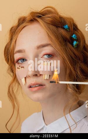 Close-up fashion portrait of girl having eyelash extension procedures. Concept of eye problems and pain allergy to glue. Burning match on background o Stock Photo