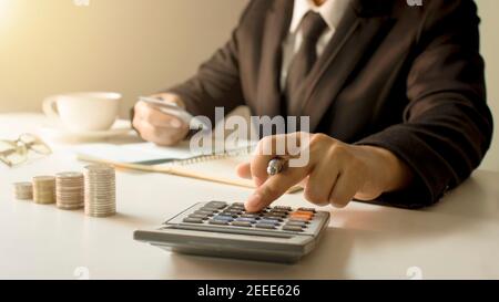 Account management and money saving concept, a close-up of a woman using a calculator to produce accounting work reports.Soft focus Stock Photo