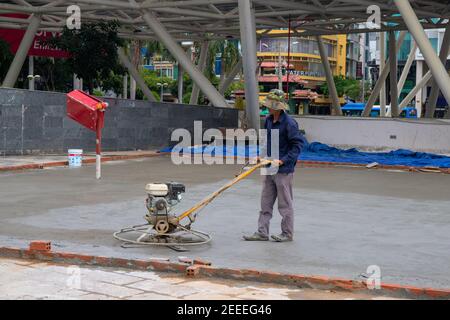 Saigon, Vietnam - 18 July, 2019: Worker makes concrete pour. Asphalt renovation street work. Park road paving process. Road construction equipment. Fl Stock Photo