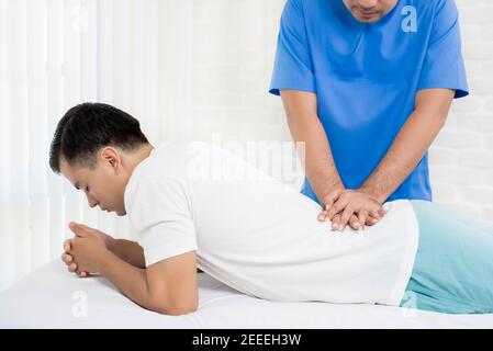 Male doctor therapist treating lower back pain patient in clinic or hospital - physical therapy concept Stock Photo