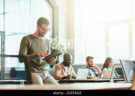 Joyous young gentleman using his tablet for work Stock Photo