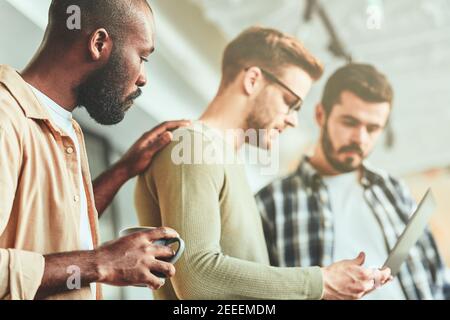 Three male coworkers being concentrated on laptop screen Stock Photo