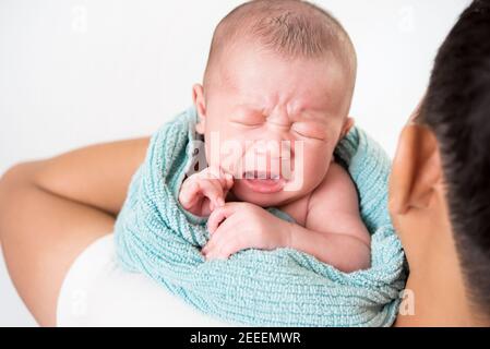 Father holding and soothing unhappy inconsolable crying little newborn baby in his arms Stock Photo
