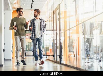Two male colleagues discussing something on way to work Stock Photo