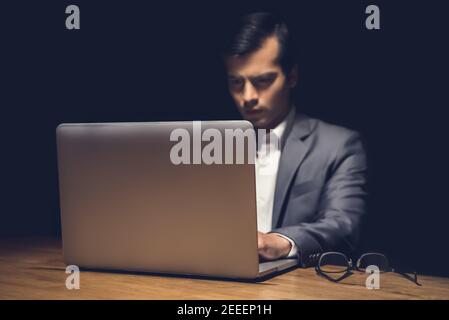 Businessman using laptop computer working late at night in dark room - workaholic and hacker concept Stock Photo