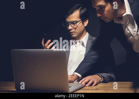 Businessmen using laptop computer working late at night in dark room - workaholic and hacker concept Stock Photo