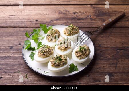 Stuffed eggs with mushrooms, cream cheese and parsley on a wooden table. Delicious homemade food Stock Photo
