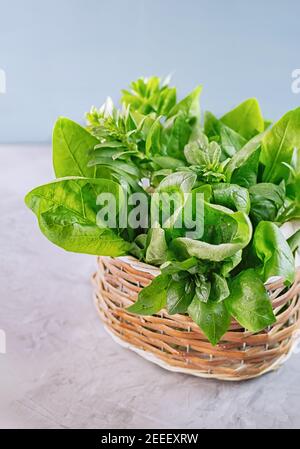 Freshly green spinach leaves placed in a wicker basket. Healthy vegan food concept. Close-up. Vertical crop. Stock Photo