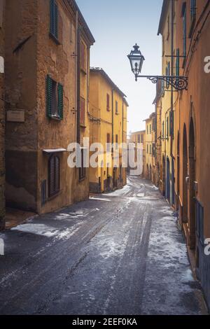 Volterra old town street during a snowfall in winter. Pisa province, Tuscany, Italy, Europe. Stock Photo