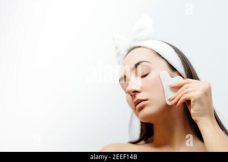 Beautiful woman using Natural Gouache Scraper Massager over face skin Stock Photo