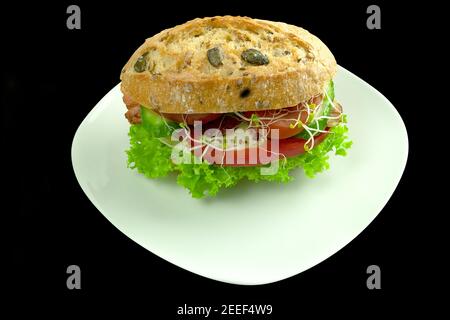Burger with fried egg and bacon with vegetables. Sandwich on a white plate with copy space for text. Delicious cheeseburger with egg and bacon and che Stock Photo