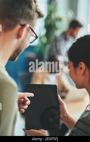 Two young people looking and pointing to blank tablet screen Stock Photo