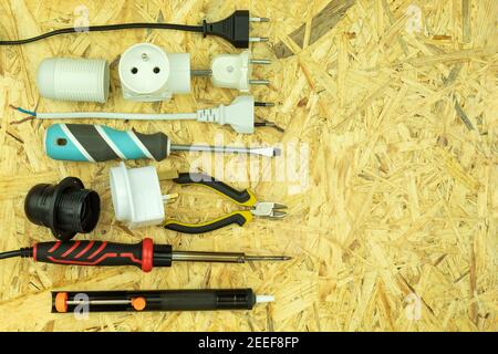 Screwdrivers and electrical tools are spread out on the table. Electrician tools on a wooden table. Screwdrivers, cartridges, plugs, wires are laid ou Stock Photo