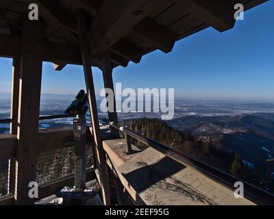 Stunning panoramic view over Rhine valley and Vosges mountain range from the top of observation tower Eugen-Keidel-Turm with binoculars in winter. Stock Photo