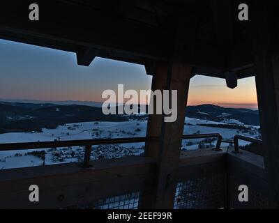 Spectacular sunset view over Black Forest with Alps on horizon from the top of observation tower Eugen-Keidel-Turm with binoculars in winter. Stock Photo