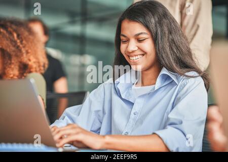 Cheerful young woman using her laptop and smiling Stock Photo