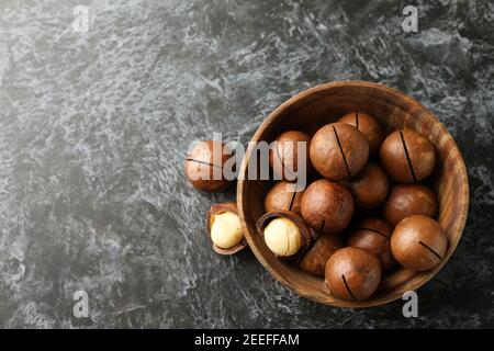 Bowl with tasty macadamia nuts on black smokey background Stock Photo