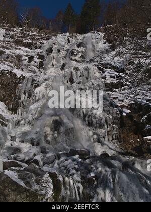 Low angle view of rocky waterfall Todtnauer Wasserfälle near Todtnau, Germany in Black Forest mountain range with frozen rocks and icicles in winter. Stock Photo