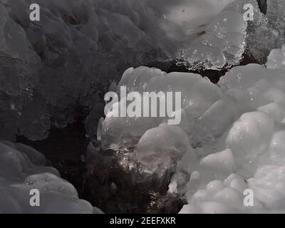 Closeup view of small mountain stream in winter season with bizarre looking frozen rocks on sunny winter day near Todtnau, Germany in Black Forest. Stock Photo
