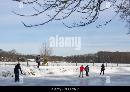 ZUTPHEN, NETHERLANDS - Feb 14, 2021: Dutch winter barren trees and snow landscape with ice skaters on frozen river Berkel Stock Photo