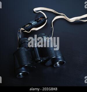 Vintage black binocular on black wooden background. Stock Photo