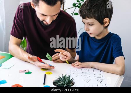 Autism awareness concept. Autism schoolboy during therapy at home with his tutor with learning and having fun together. Stock Photo