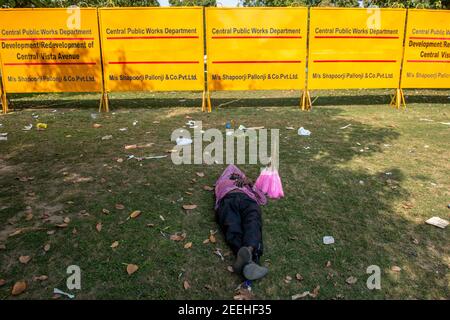 New Delhi, India. 15th Feb, 2021. A cotton candy seller seen sleeping in front of the large metal sheets at a construction site near the India Gate Lawn.Central Vista Avenue Redevelopment Project begins near Rajpath Under the redevelopment of the 3 km long Central Vista Avenue in Lutyens Delhi. Credit: SOPA Images Limited/Alamy Live News Stock Photo